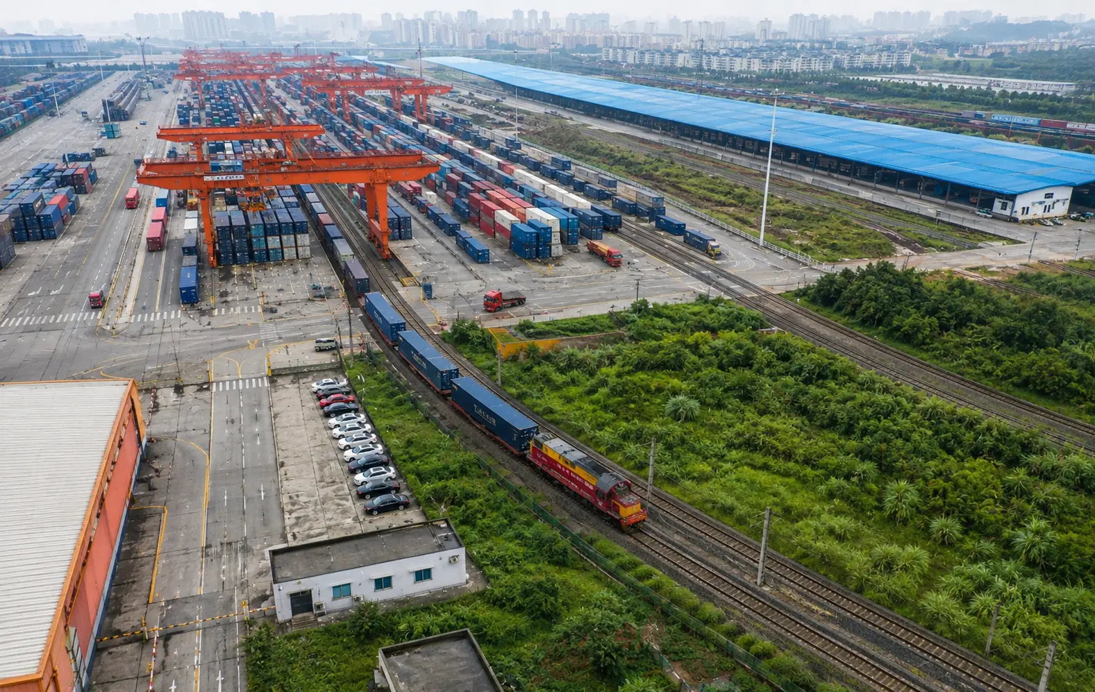 ศูนย์ขนส่งสินค้าทางรถไฟในจีนที่มีตู้คอนเทนเนอร์ เครน และขบวนรถไฟอยู่ภายในพื้นที่