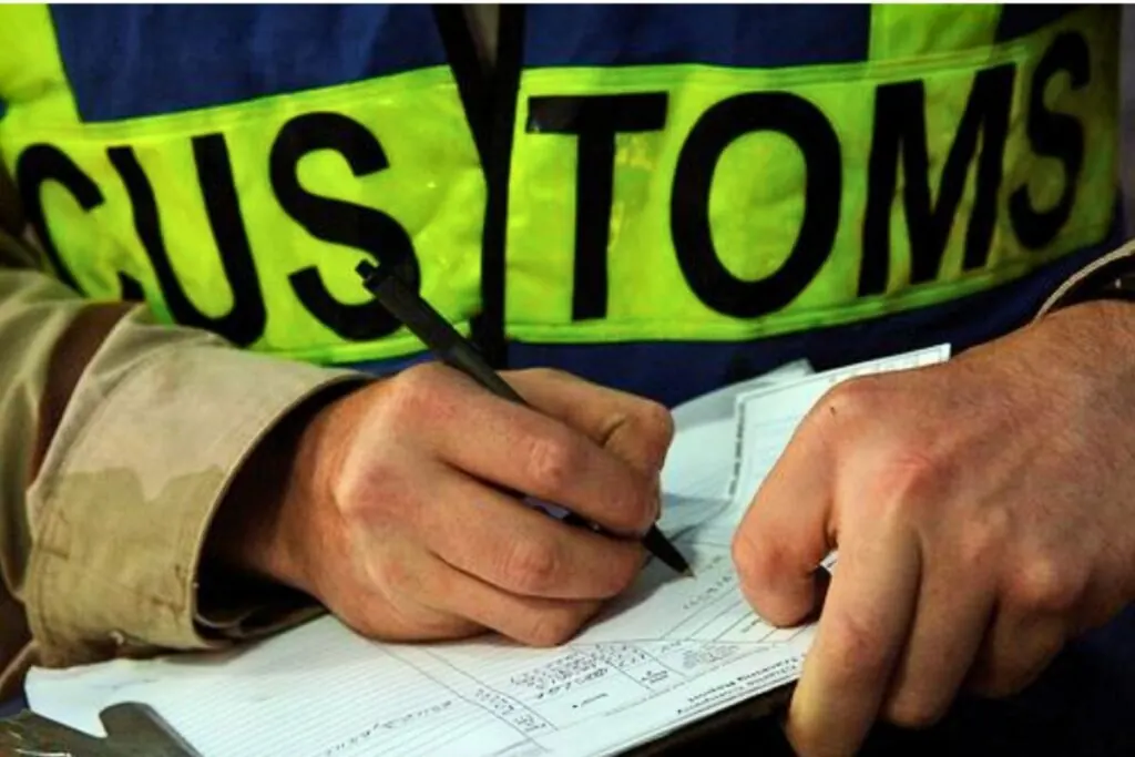 ผู้สวมเสื้อ CUSTOMS กำลังตรวจและบันทึกเอกสาร